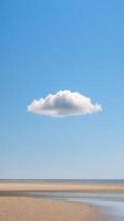 A cloud floating in the sky above a beach photo