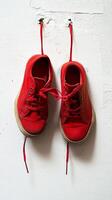A pair of red shoes hanging on a wall photo