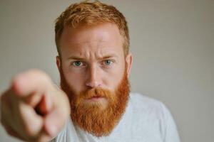 A man with a red beard pointing at something photo