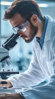 A man in a lab coat looking through a microscope photo