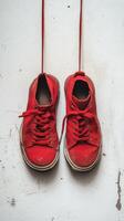 A pair of red sneakers hanging from a wall photo