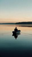 A man is sitting in a boat on a lake photo