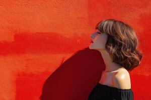 A woman is standing in front of a red wall photo
