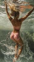A woman in a pink bikini is underwater photo