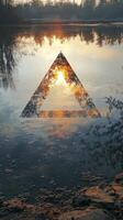 A triangle is reflected in the water at sunset photo