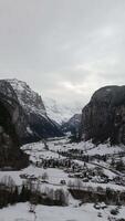 Lauterbrunnen Valley and Snowy Mountains on Cloudy Winter Day. Swiss Alps. Switzerland. Aerial View. Moving Backwards and Upwards. Vertical video