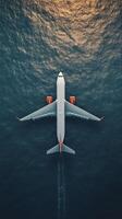An airplane flying over the ocean at sunset photo