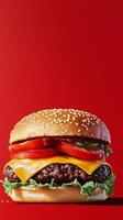 A hamburger with cheese, lettuce and tomatoes on a red background photo