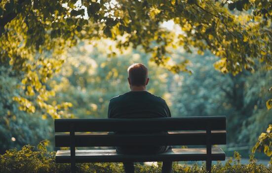 A man sitting on a bench in the middle of a park photo