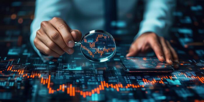 Businessman using magnifying glass to look at stock market data photo