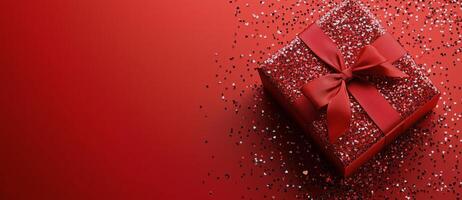 Red gift box with silver confetti on red background photo