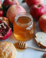 A jar of honey, bread, apples and pomegranates photo