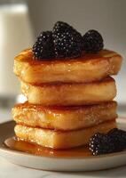 A stack of pancakes with blackberries and syrup photo