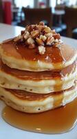 A stack of pancakes with syrup and nuts on top photo