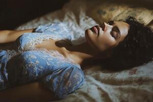 A woman in a blue dress is laying on a bed photo