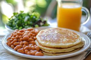 A plate of pancakes, beans and a glass of orange juice photo