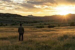 A man standing in a field looking at the sun photo