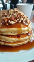 A stack of pancakes topped with nuts and syrup photo