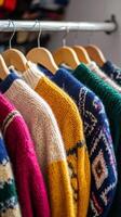 A row of colorful sweaters hanging on a rack photo