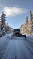 A snow plow driving down a snowy road photo