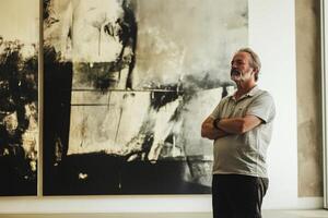 A man standing in front of a large painting photo