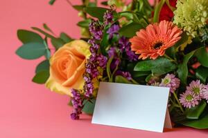 A bouquet of flowers and a blank card on a pink background photo