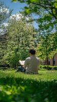 A man sitting in the grass reading a book photo