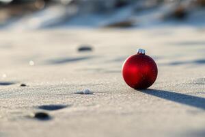 A red christmas ornament sitting on the beach photo