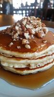 A stack of pancakes topped with nuts and syrup photo