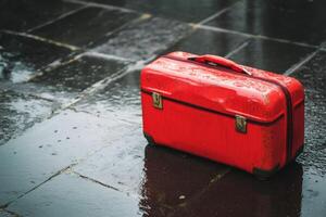 A red suitcase sitting on a wet pavement photo