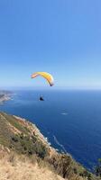 A paraglider flying over the ocean on a sunny day photo