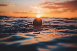 A person swimming in the ocean at sunset photo