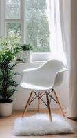 A white chair and a potted plant in front of a window photo
