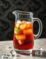 Refreshing iced tea with mint leaves served in a glass pitcher on a marble surface photo