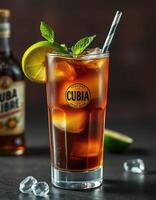 Refreshing Cuba Libre cocktail served with ice and garnished with lime and mint in a glass on a dark background photo