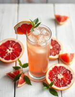 Refreshing grapefruit drink garnished with mint on a wooden table surrounded by sliced grapefruit photo