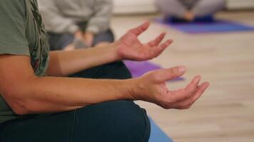Male hands performing Gyan Mudra gesture during meditative practice in yoga class, representing inner calm, wisdom cultivation, and spiritual connection through mindful movement video