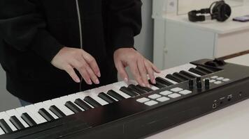 Close up of a female musician skillfully playing an electronic keyboard in a modern recording studio, immersed in the process of composing a new song or practicing for an upcoming performance video