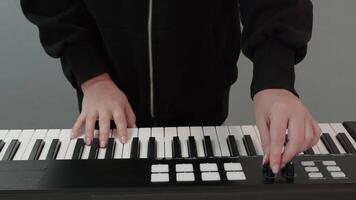 Close up of female musician's hands playing a modern electronic keyboard with black and white keys and various control buttons, creating music in a studio setting video