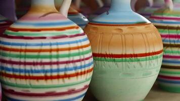 Tracking shot of various colorful clay vases. Beautiful ceramic containers on table. They are at workshop. video