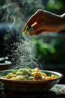 A person sprinkling salt on a dish of pasta photo