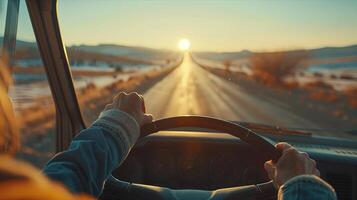A person driving a car on a road with the sun setting behind them photo