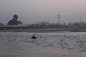 A man is rowing a boat in a river photo