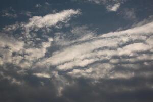 A plane flying in the sky with some clouds photo
