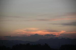 A plane flying over a mountain range at sunset photo