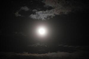 The moon is shining brightly in the dark sky photo