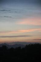 A plane flying over a mountain at sunset photo