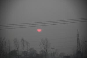 The sun is setting behind a power line photo