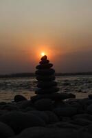 A stack of rocks on the beach at sunset photo
