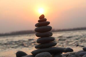 A stack of rocks on the beach at sunset photo
